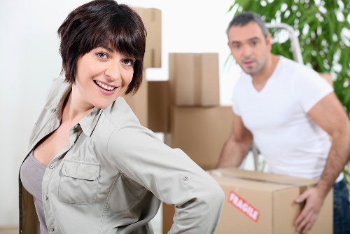 Professional movers carrying furniture through a West Ham street